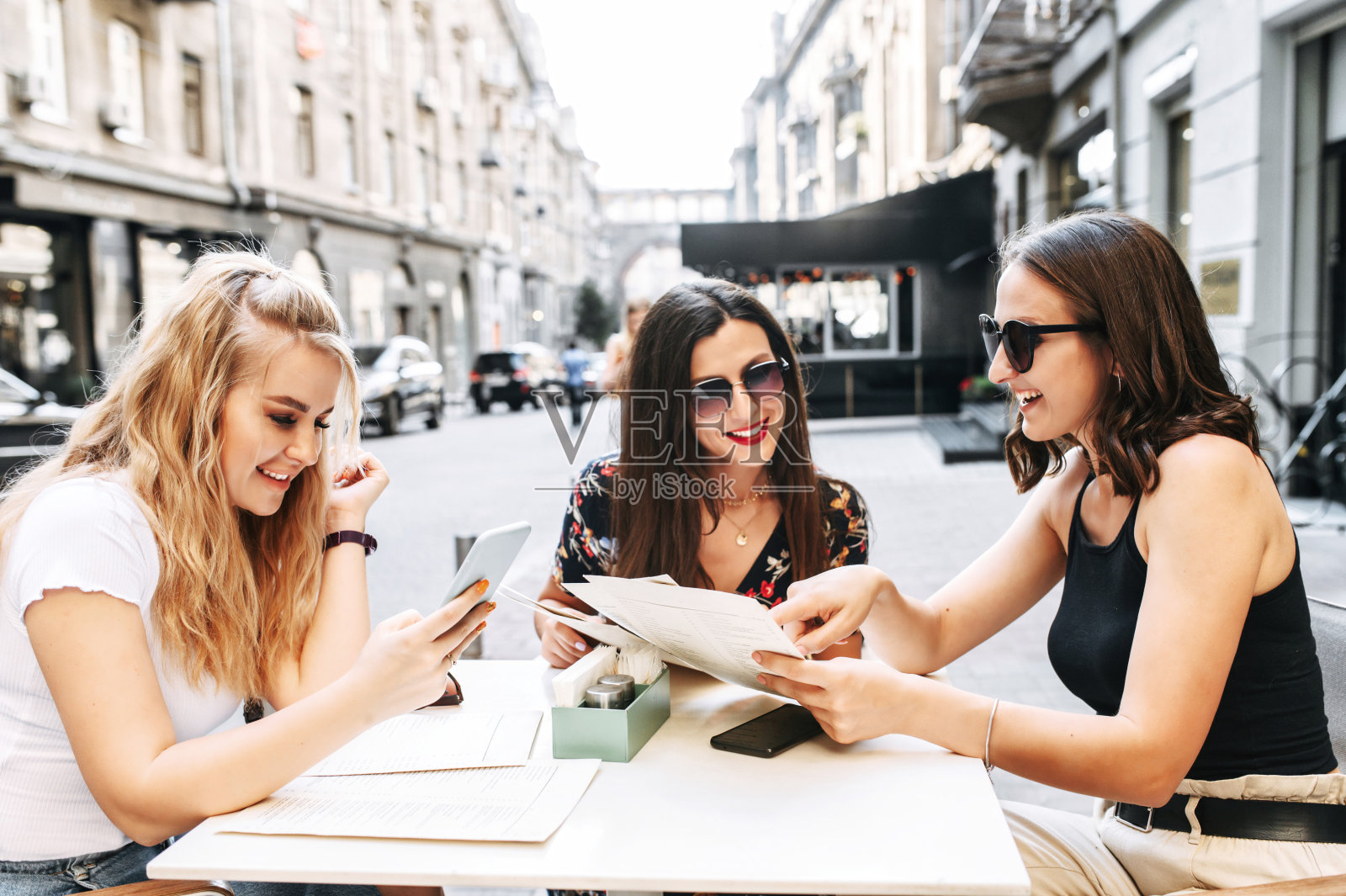 年轻漂亮的女孩坐在露天咖啡馆里照片摄影图片