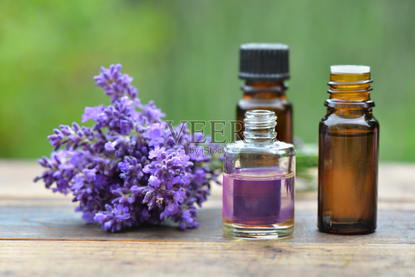 花园里的木桌上放着几瓶精油和一束薰衣草照片摄影图片