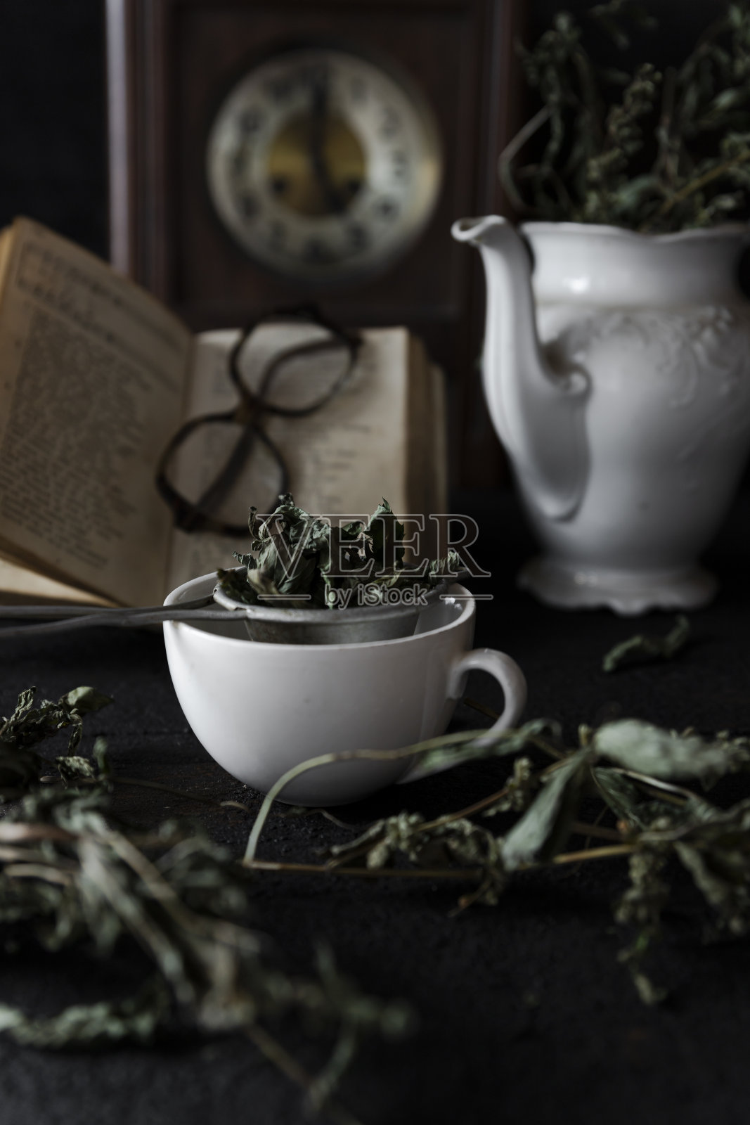 茶。一杯茶和茶壶在木桌与旧时钟和书的背景照片摄影图片