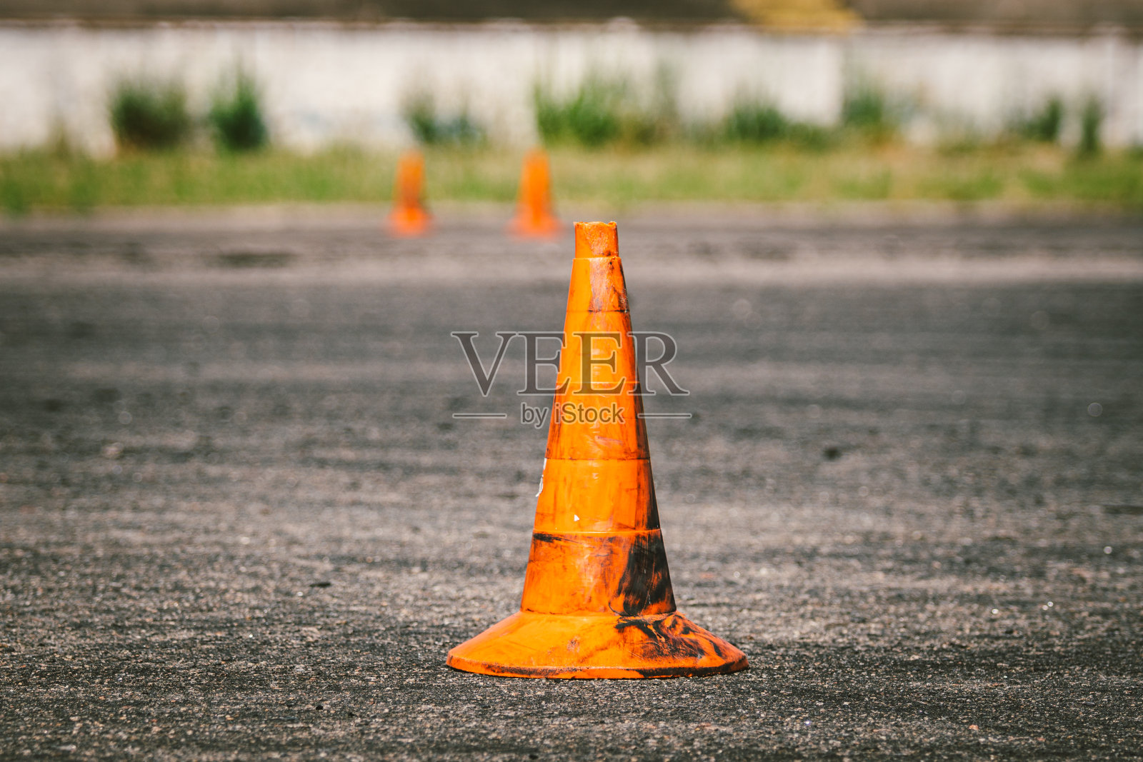 一个旧的肮脏的橙色交通锥在现场驾驶培训或汽车学校的特写。停车场，极限驾驶体育场的塑料红色标记。驾驶学校的概念照片摄影图片