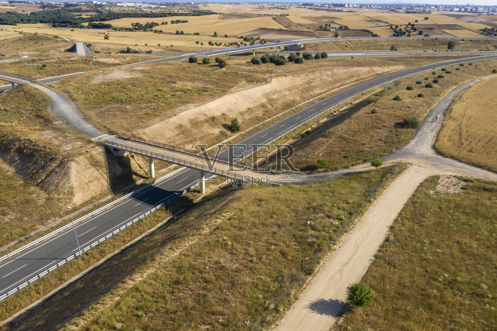 小桥下干草地中间的马路照片摄影图片