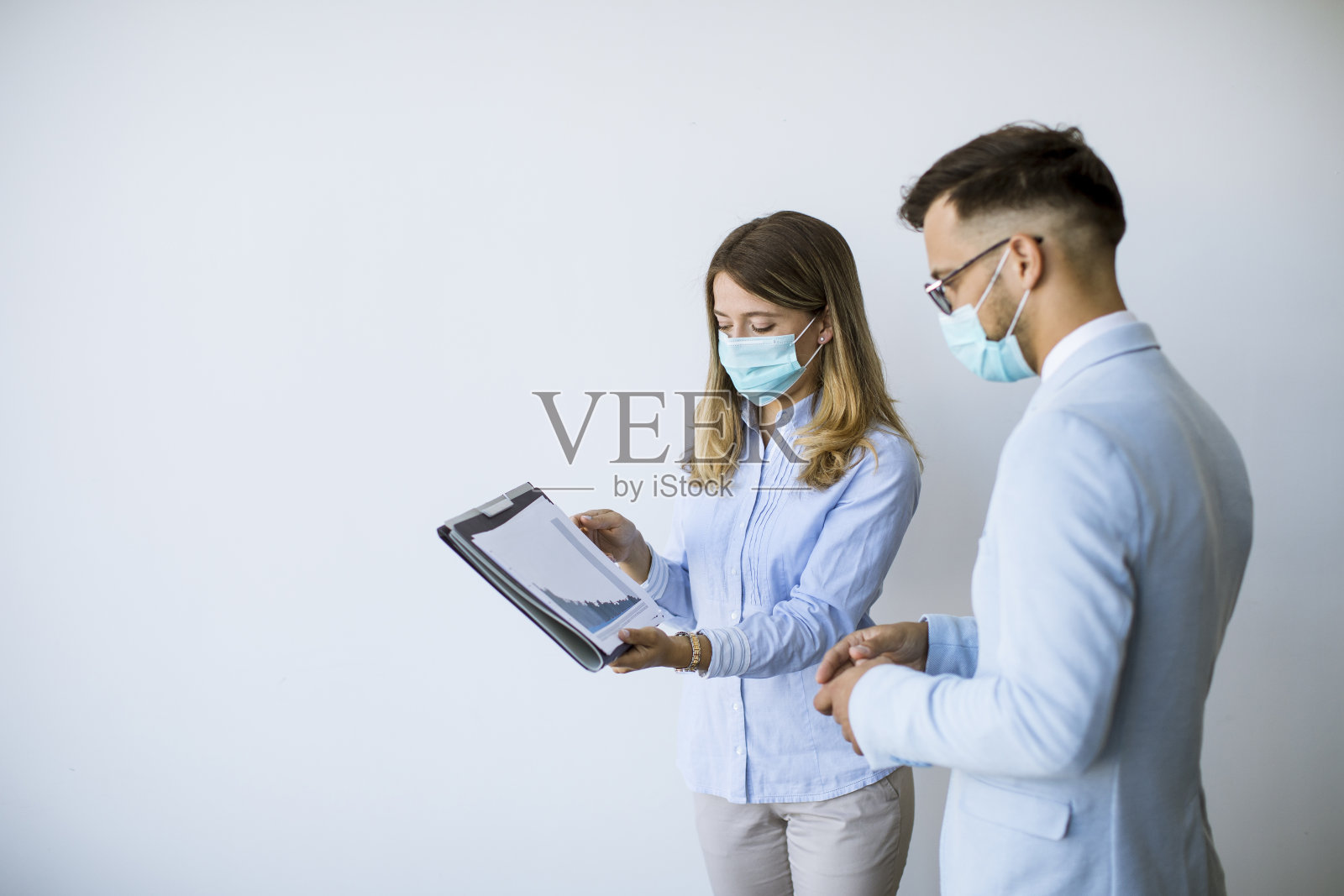 业务伙伴戴着口罩站在办公室看业务成果，以防病毒照片摄影图片