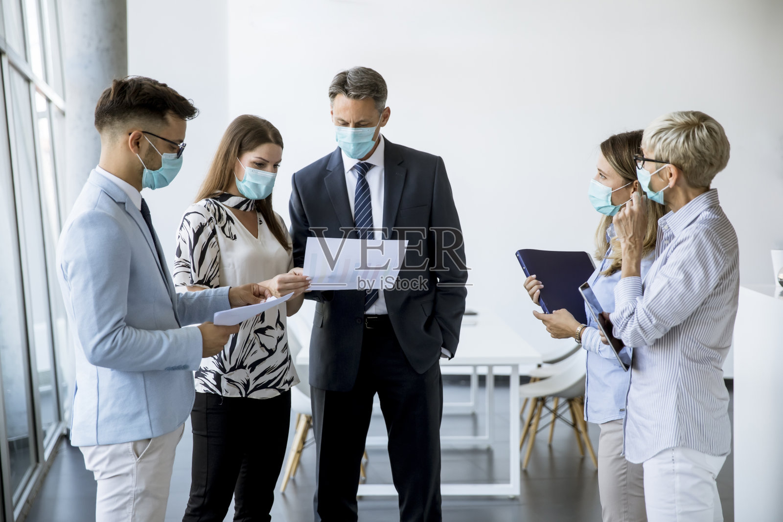 业务伙伴戴着口罩站在办公室看业务成果，以防病毒照片摄影图片