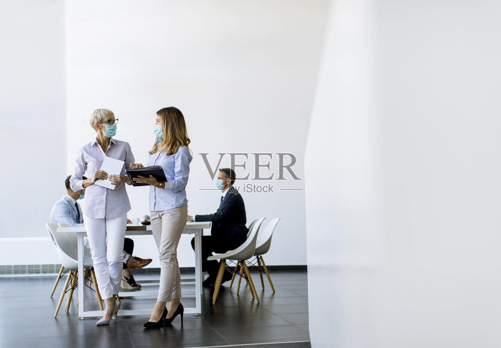 两位女商人戴着防毒面具在办公室交谈照片摄影图片