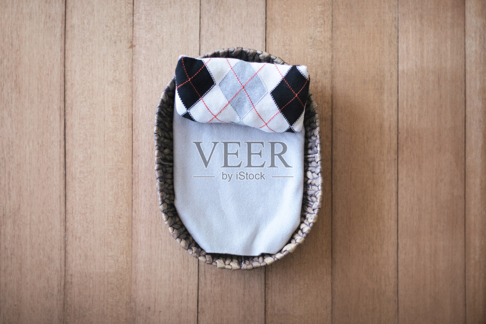 新生数字背景-浅灰色层的自然编织篮子和菱形灰色，棕色和橙色的枕头在木质背景上。刚出生的男孩的背景。照片摄影图片