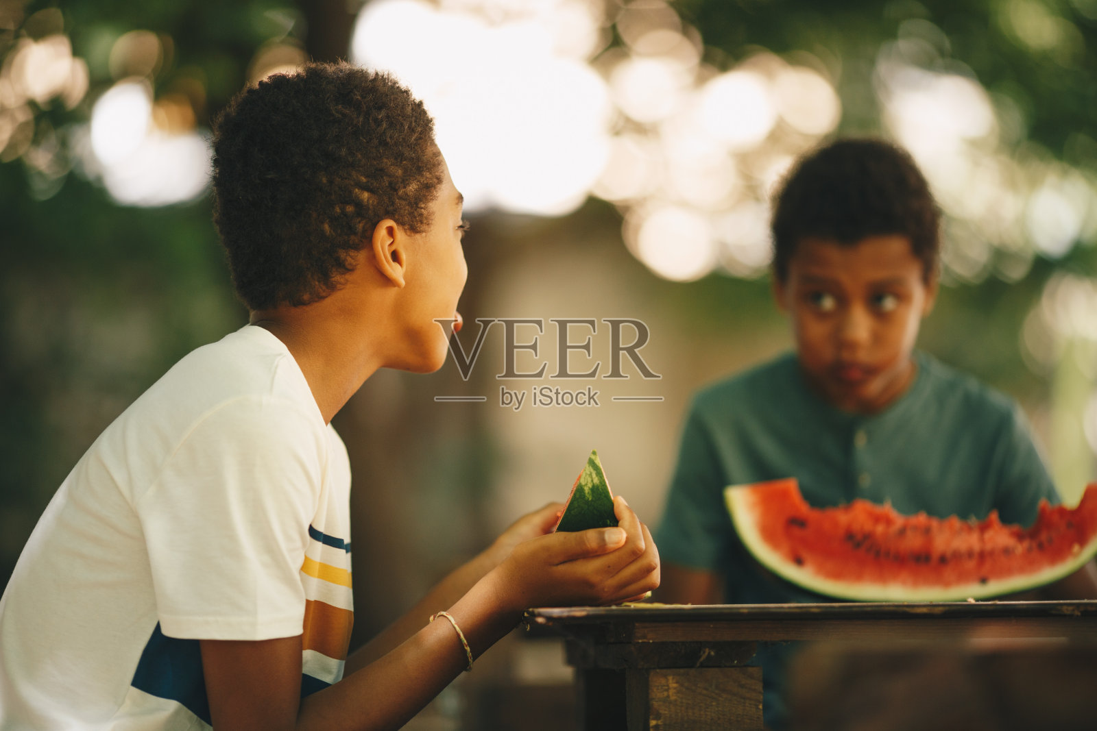 两个年轻人坐着，一边吃着西瓜一边聊天照片摄影图片