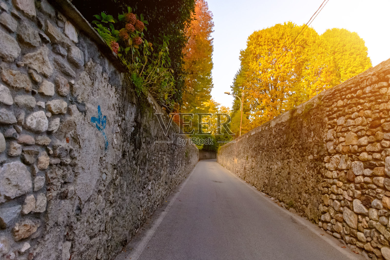 沿着高高的石墙的路。意大利。Angera。爽肤水照片摄影图片