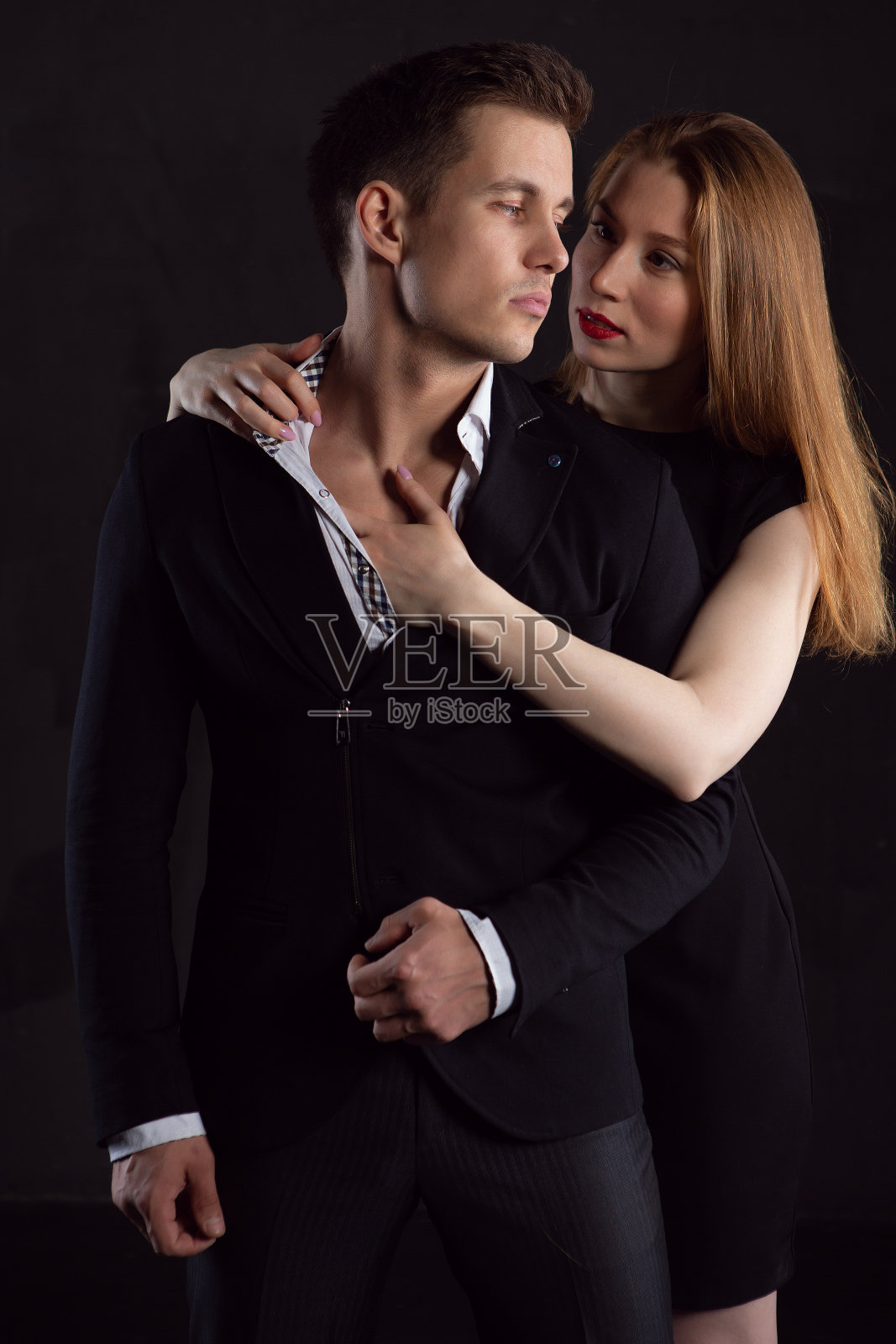 穿着黑色连衣裙的迷人女子轻抚男人敞开的衬衫胸膛照片摄影图片