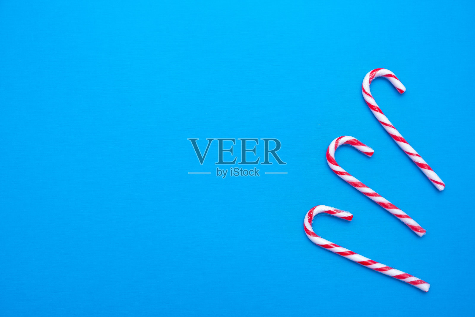 白色和红色的糖果拐杖在蓝色的背景，复制空间照片摄影图片