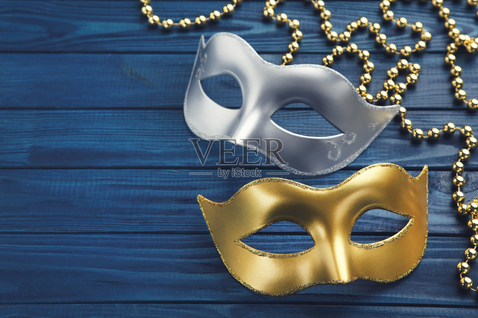 蓝色的木桌上放着狂欢节面具上的珠子照片摄影图片