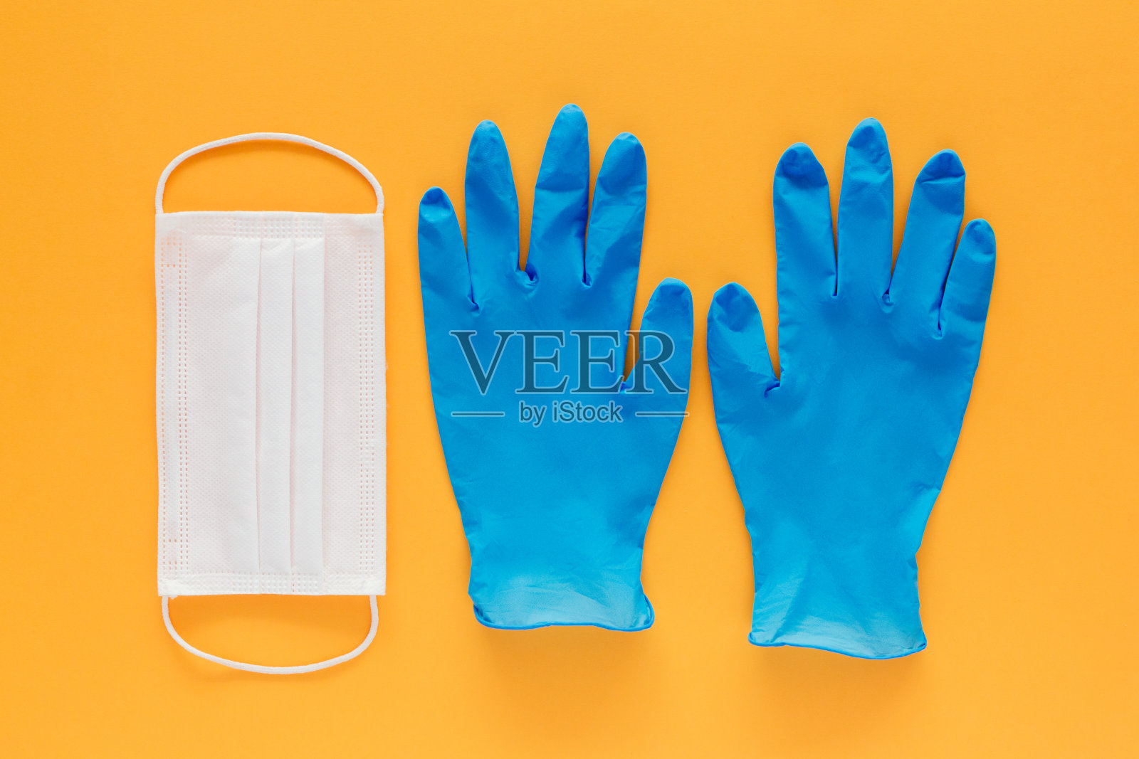 黄色背景上的一个口罩和两只医用手套的库存照片。冠状病毒预防照片摄影图片