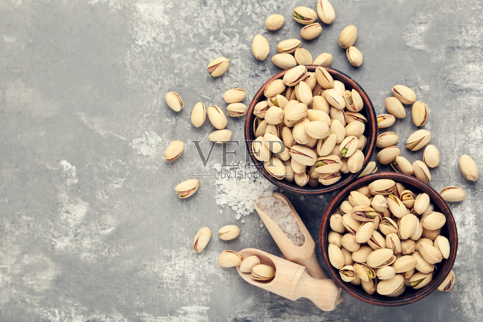 美味的开心果在碗和勺子在灰色的背景照片摄影图片