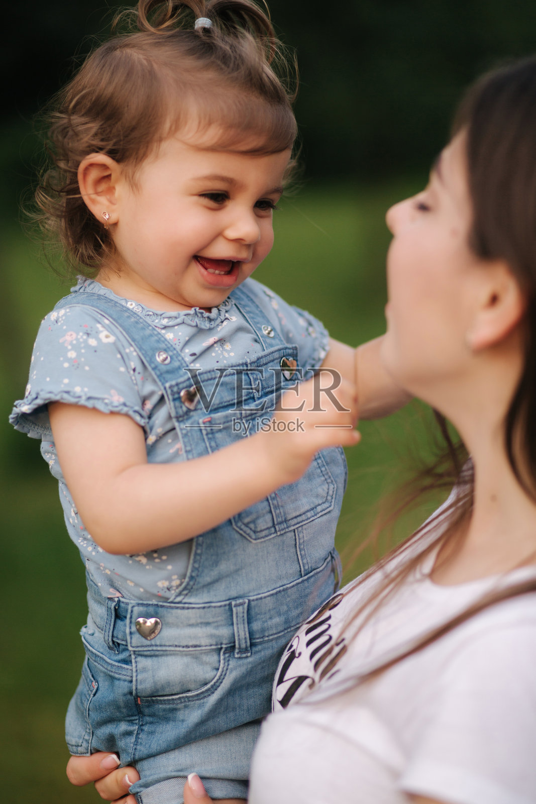 漂亮的小女儿，18个月大，在妈妈的手上。可爱女孩的微笑照片摄影图片