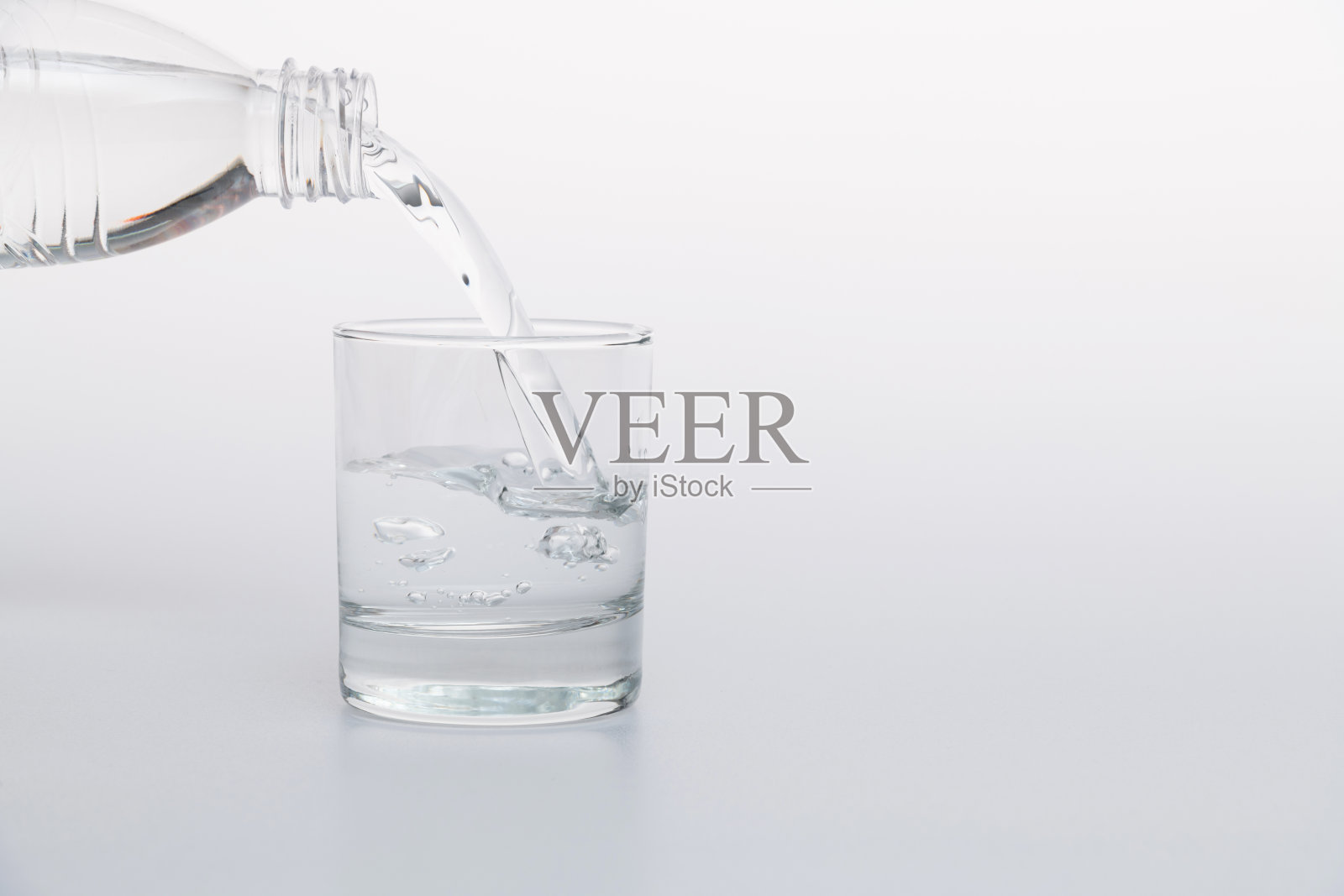 一瓶水倒进一个玻璃杯里照片摄影图片