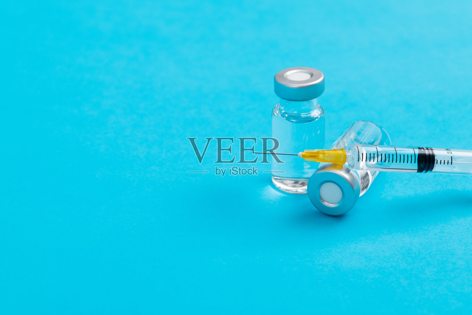 蓝色背景上的注射器和小瓶照片摄影图片