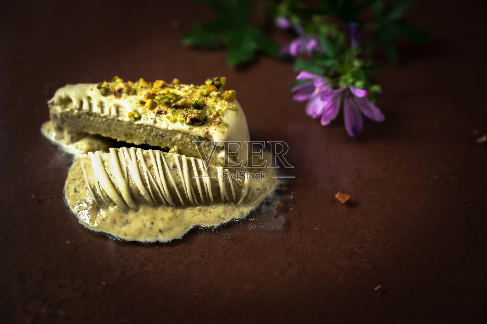 切片开心果冰棒融化在玻璃背景与花。照片摄影图片