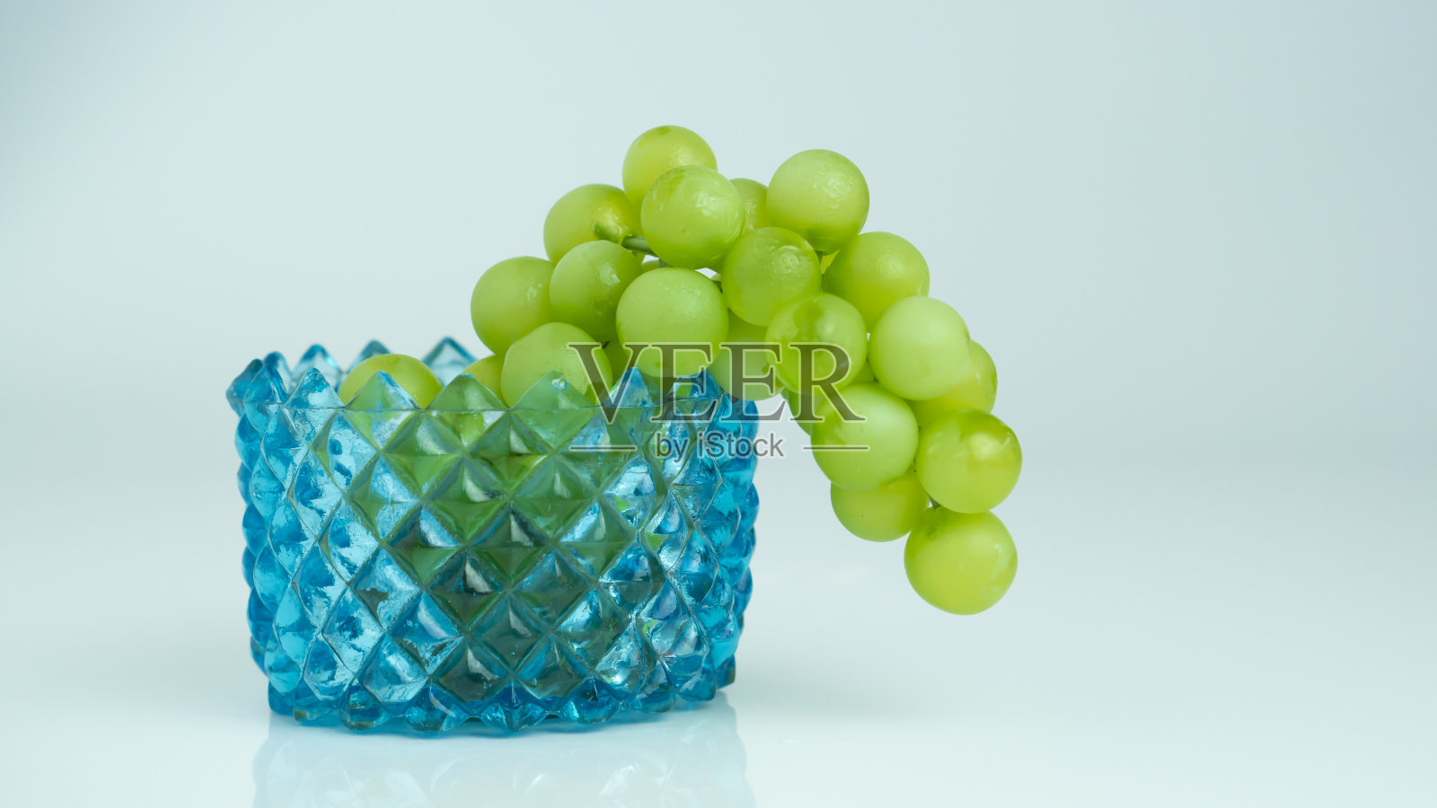 绿色的葡萄放在蓝色的玻璃碗上照片摄影图片
