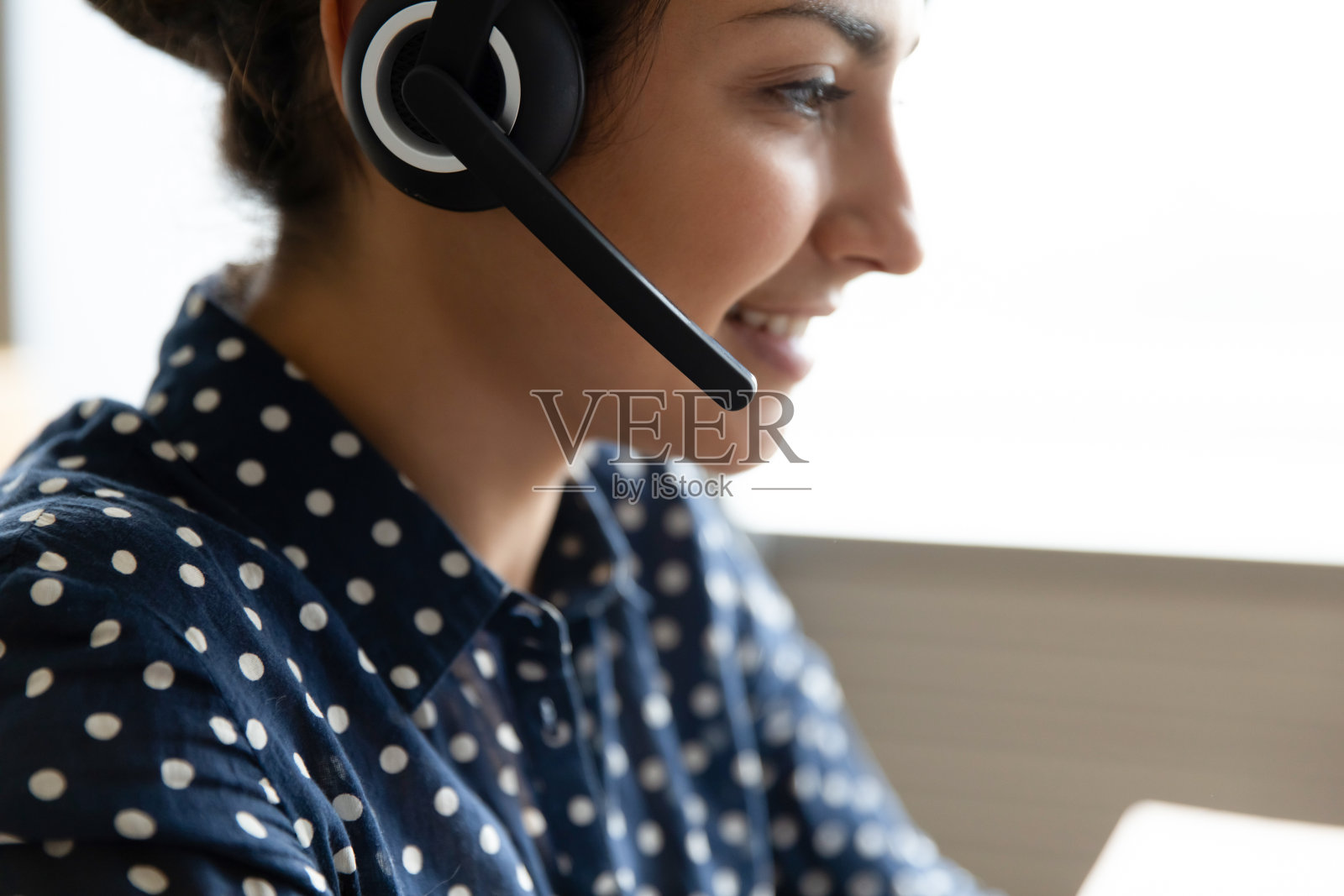 令人愉快的漂亮微笑的印度女人戴着耳机和麦克风。照片摄影图片