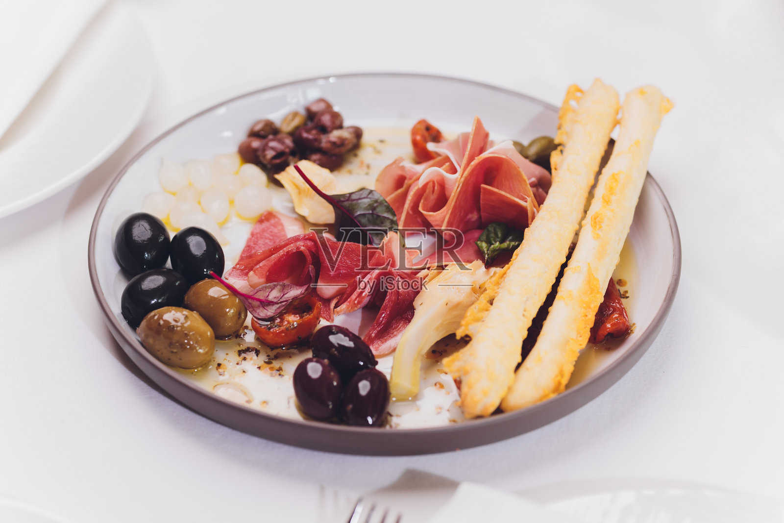 肉开胃菜的选择。意大利腊肠，意大利熏火腿，面包棒，法式长棍，橄榄和番茄干，选择性的重点。照片摄影图片