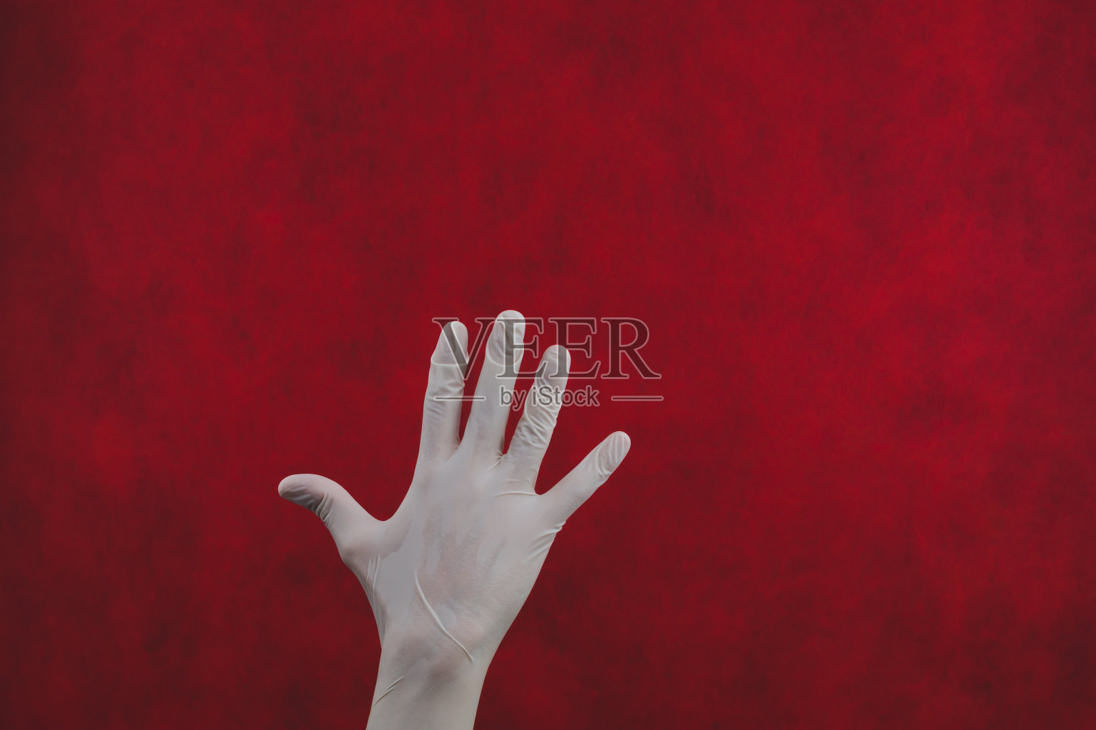 红色背景上戴着白色医用手套的手照片摄影图片