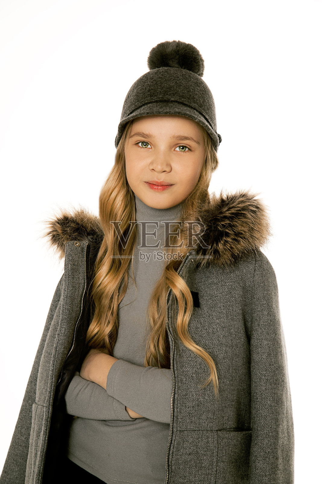 一个漂亮的金发女孩，一头卷发，穿着时髦的温暖的衣服，对着白色背景的相机微笑。与世隔绝，8-10岁电子学习。准备好上学了。肖像照片照片摄影图片