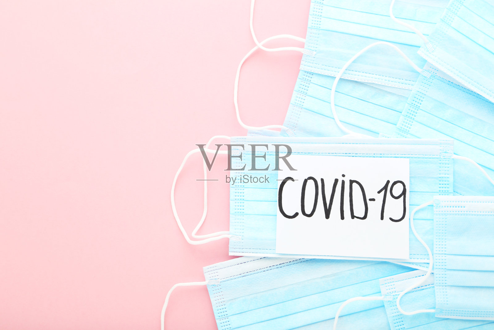 粉色背景文字Covid-19的医用口罩照片摄影图片