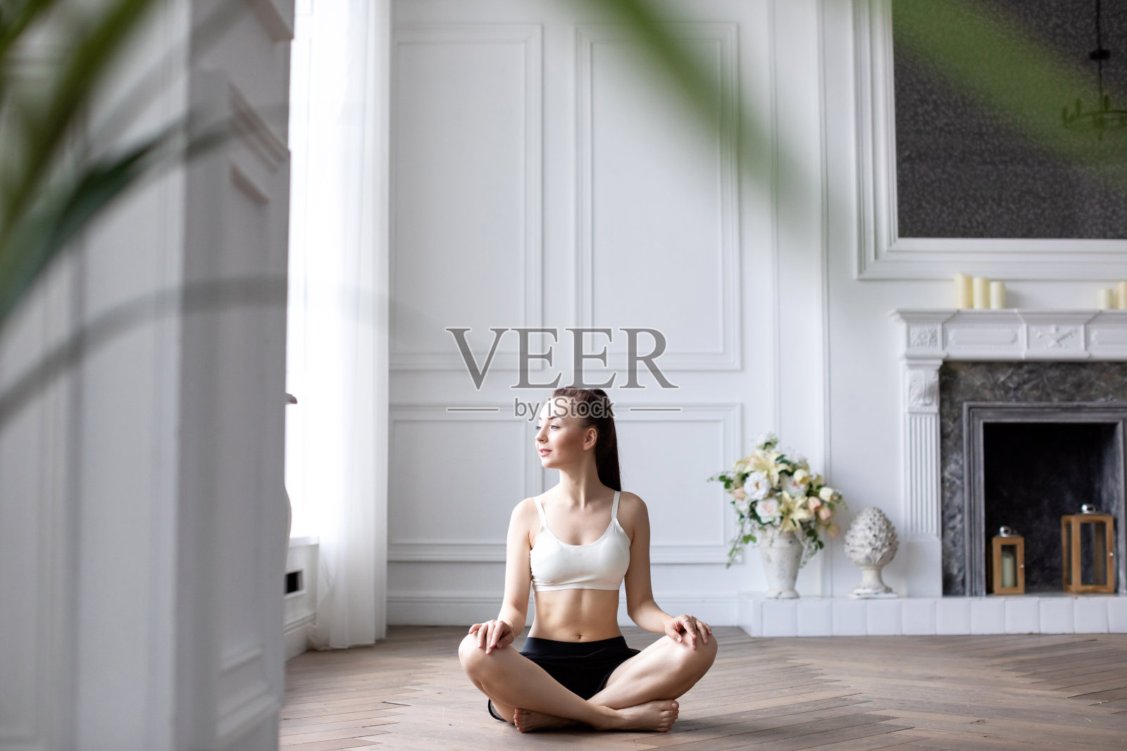 年轻女子在家里做瑜伽莲花姿势。照片摄影图片