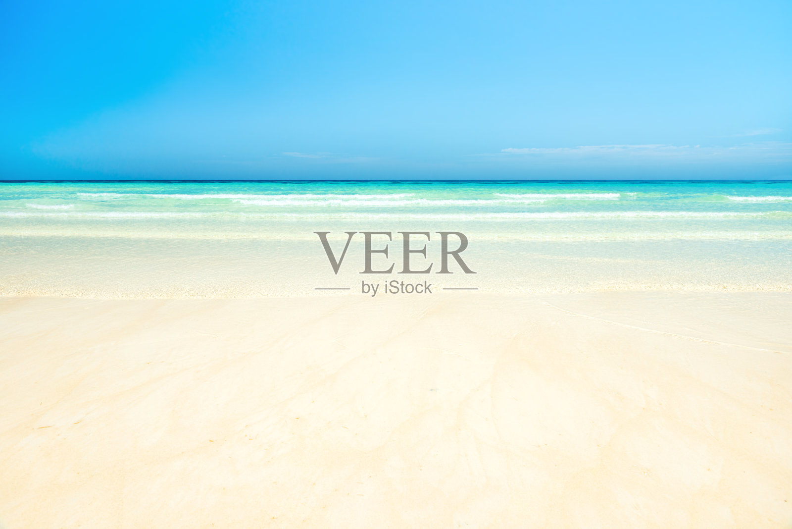 蓝色的天空下，白色的沙滩和清澈的海水照片摄影图片