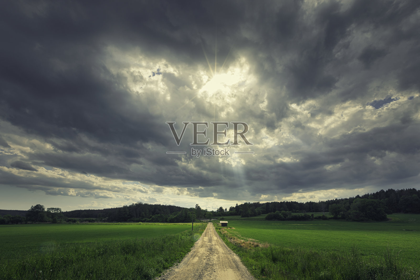 阳光和乌云笼罩在乡间小路上照片摄影图片