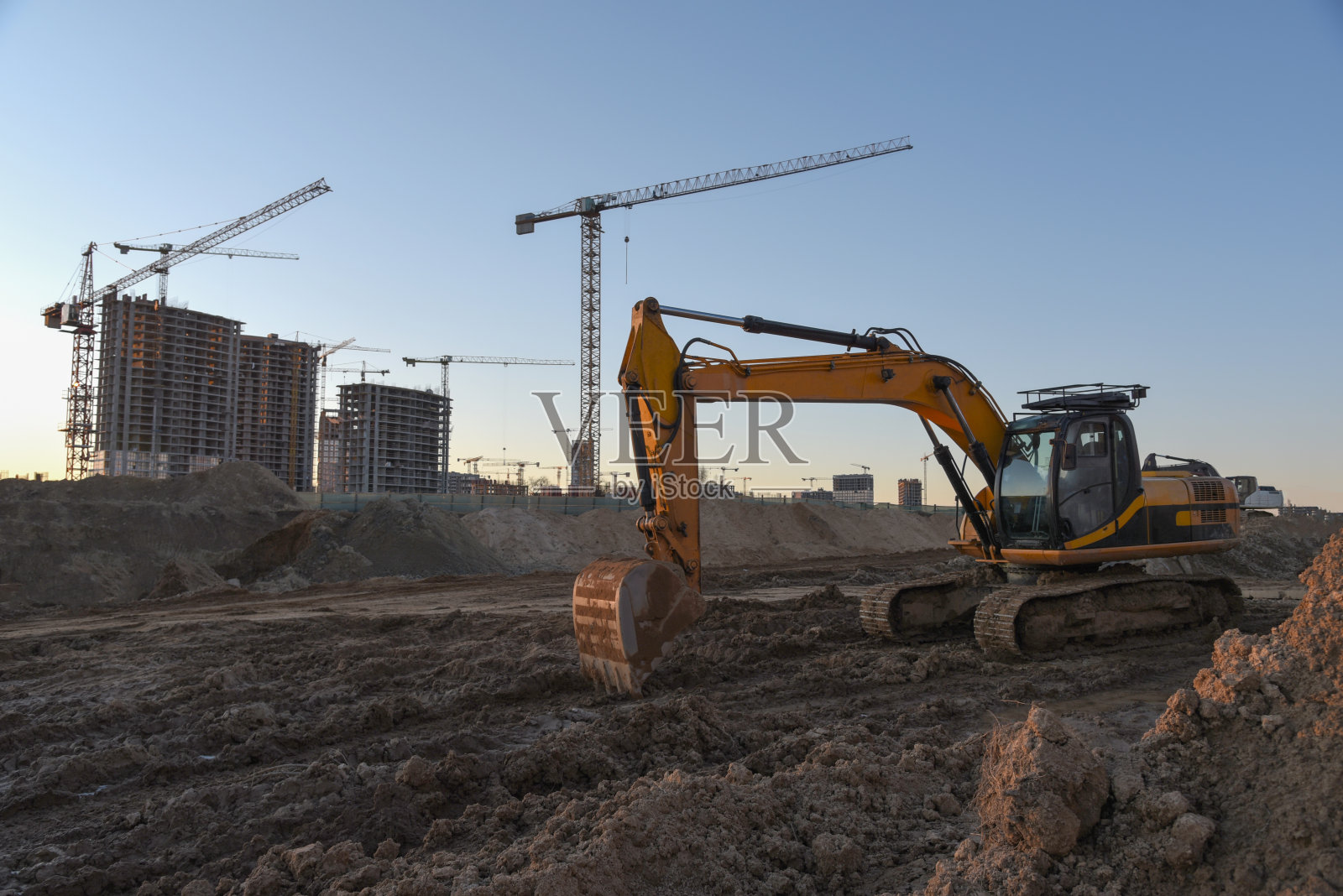 挖掘机在土方工程施工现场工作。挖土机挖掘建筑基础。铺设污水管道。用于道路工程、挖掘、装载、提升和运输货物的重型机械照片摄影图片