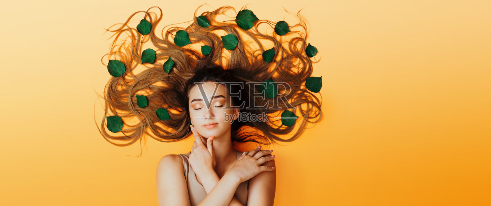 夏日少女躺在以绿叶为背景的长发为树冠上，观念女性自然美容护理，头顶少女高角观照片摄影图片