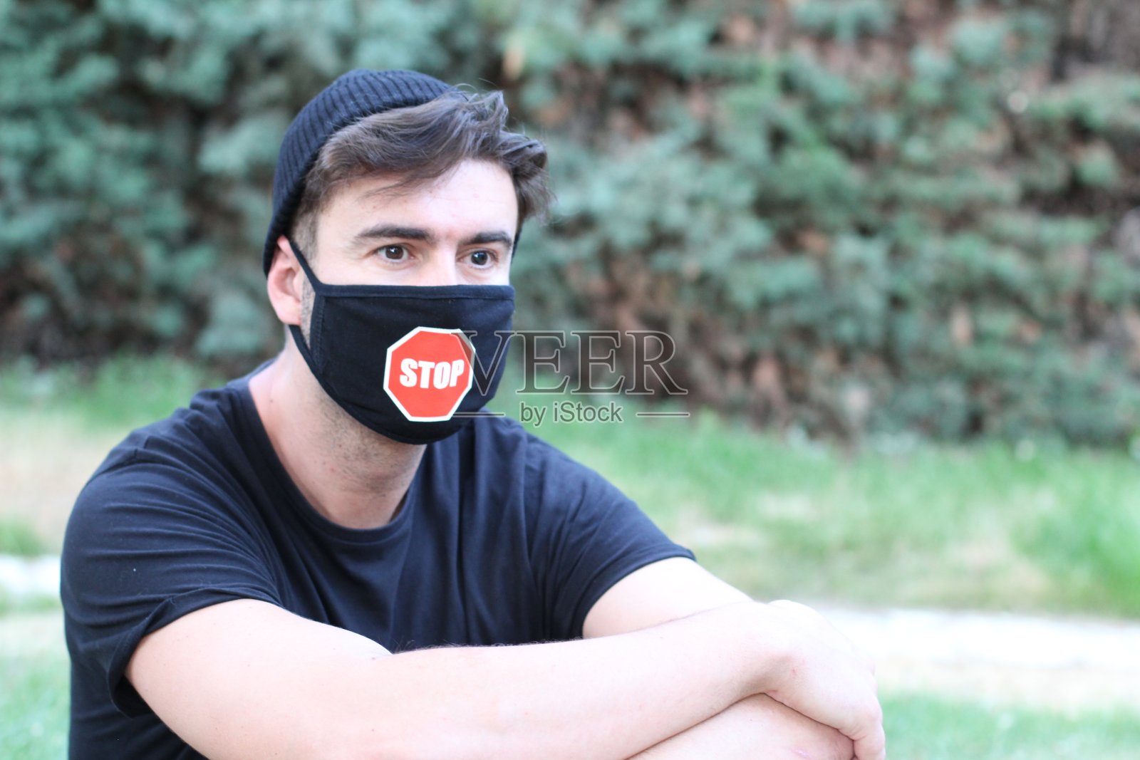 戴防护口罩拿着停止标志的年轻男人照片摄影图片