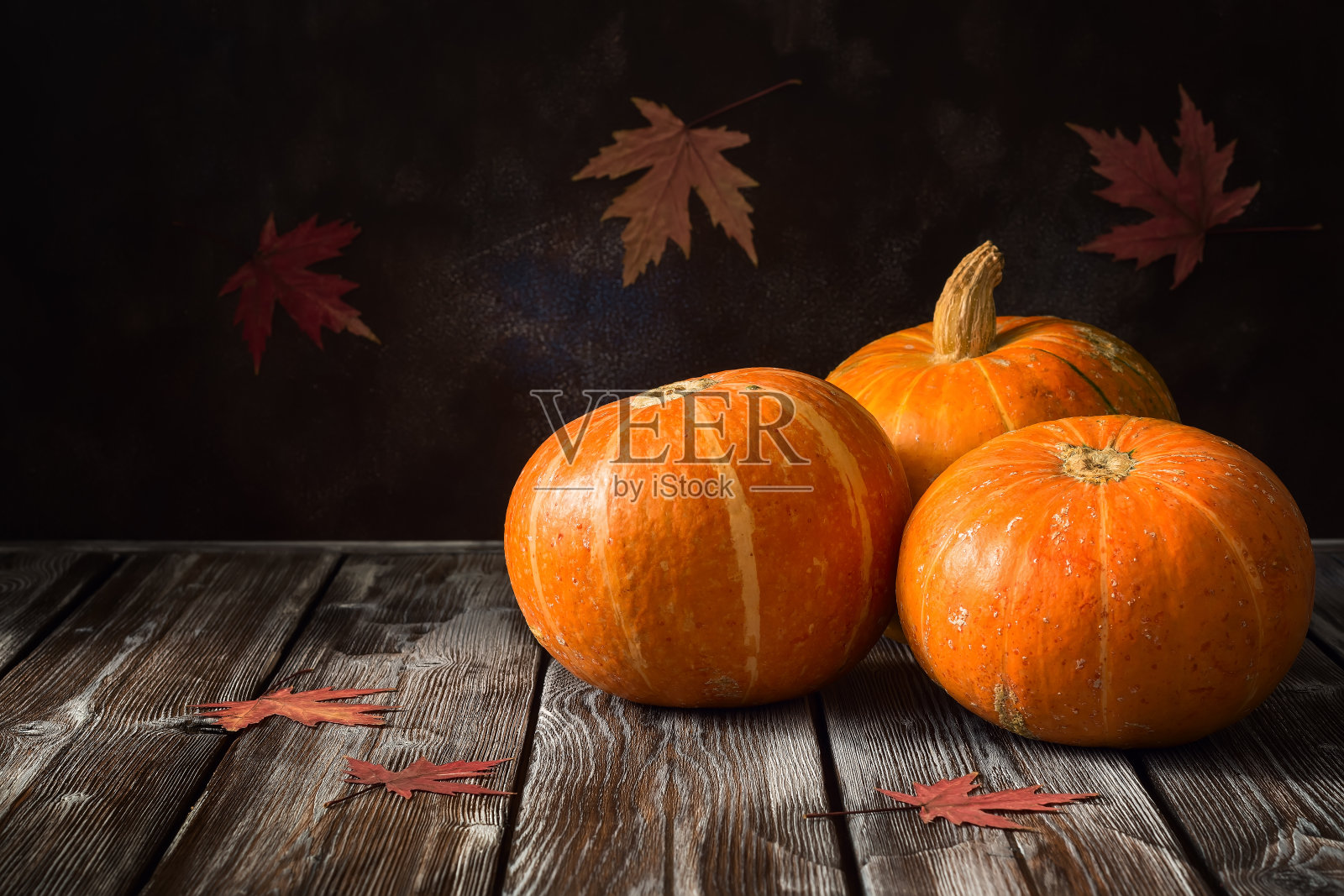 一张用枫叶装饰的老式木桌上放着生南瓜。万圣节和感恩节的概念。有选择性的重点。照片摄影图片