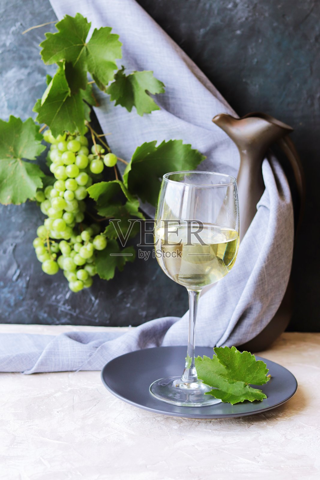 酒杯里放着年轻的葡萄酒，灰色背景上放着一串葡萄，桌上放着夏天的季节，家常菜照片摄影图片