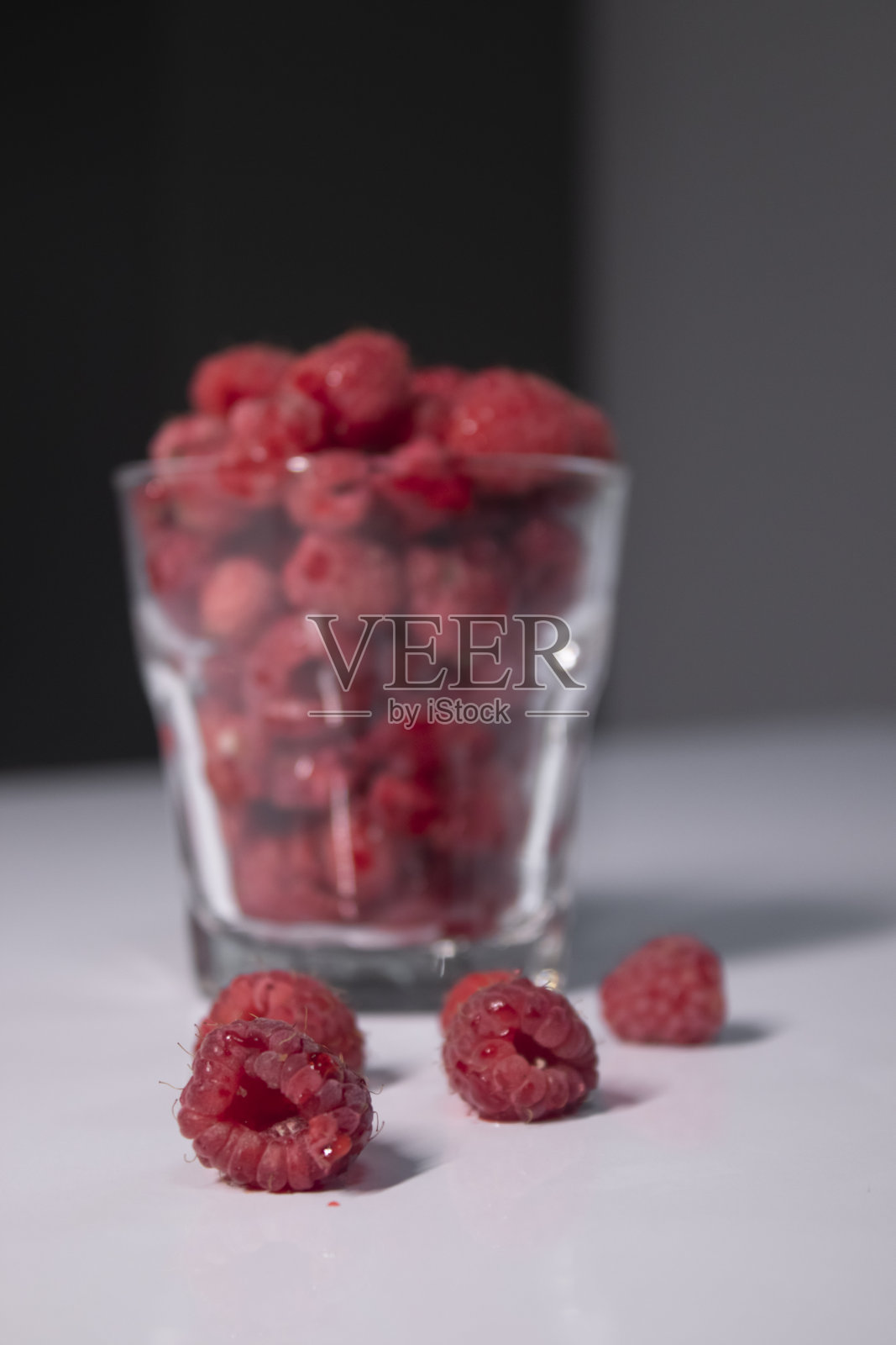 灰色厨房的白色桌子上放着透明玻璃和覆盆子照片摄影图片