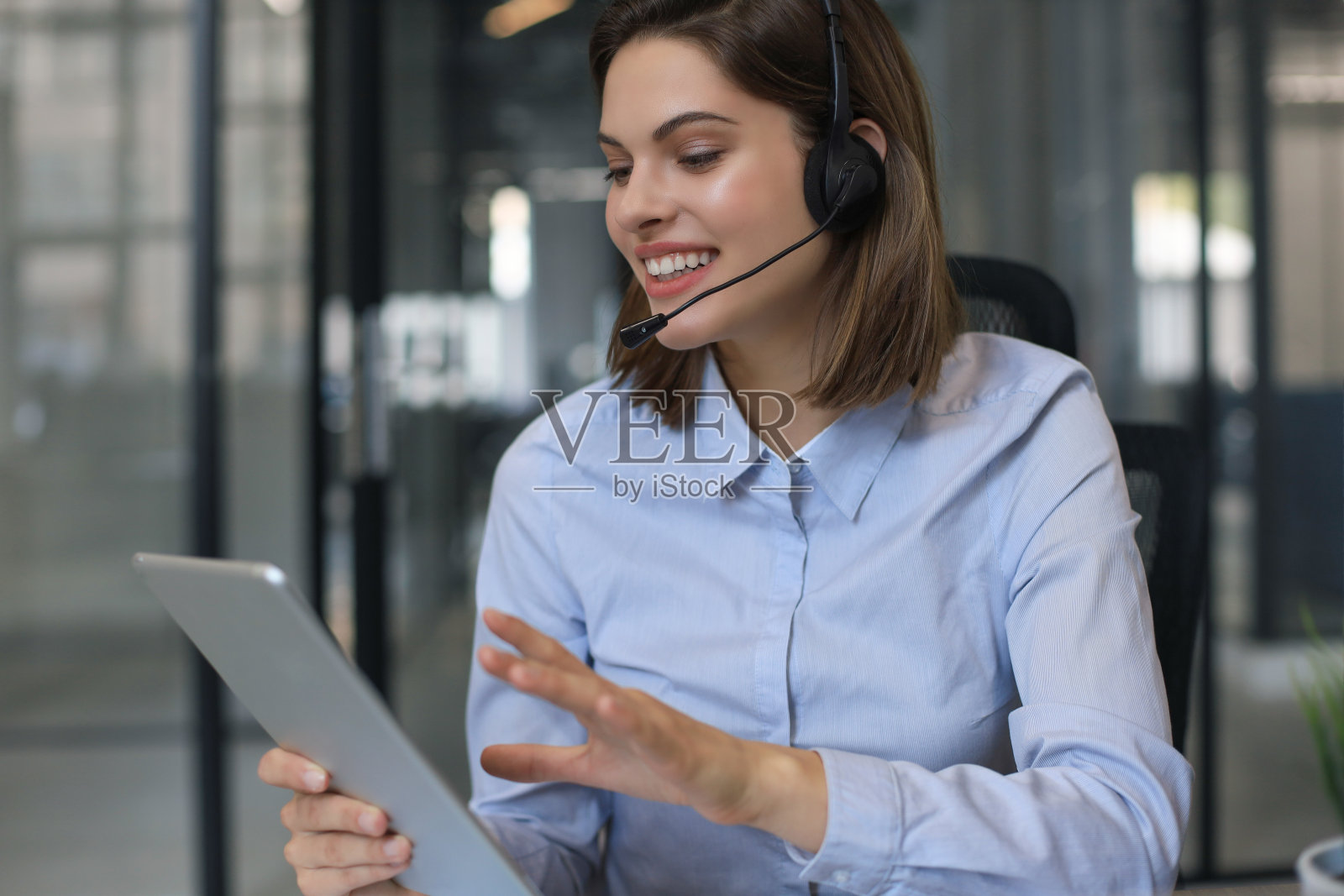 愉快的女经理坐在办公桌前，用无线连接的数码设备执行公司任务。照片摄影图片