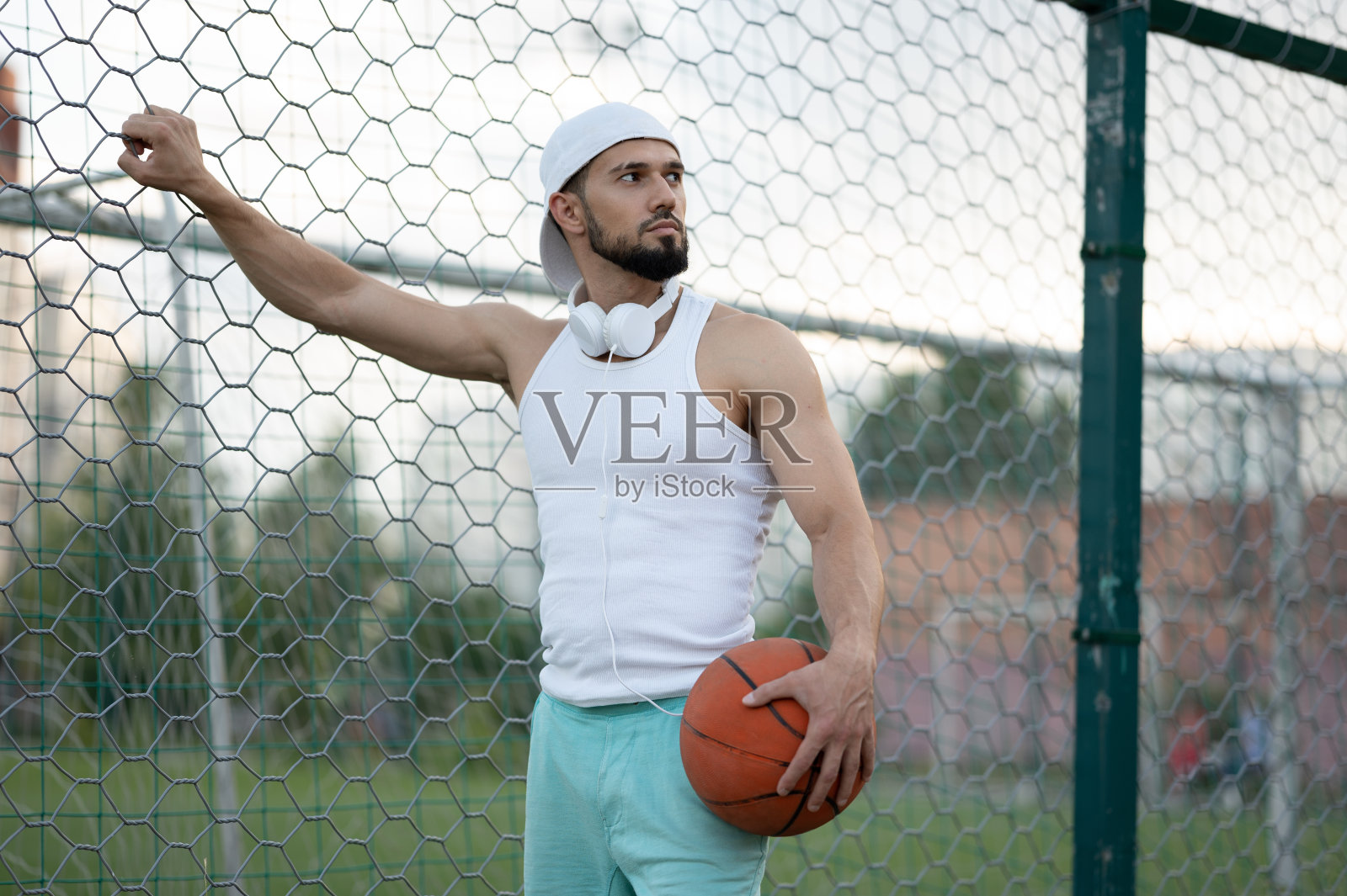 一名男子站在街道的围栏附近，手里拿着一个篮球照片摄影图片