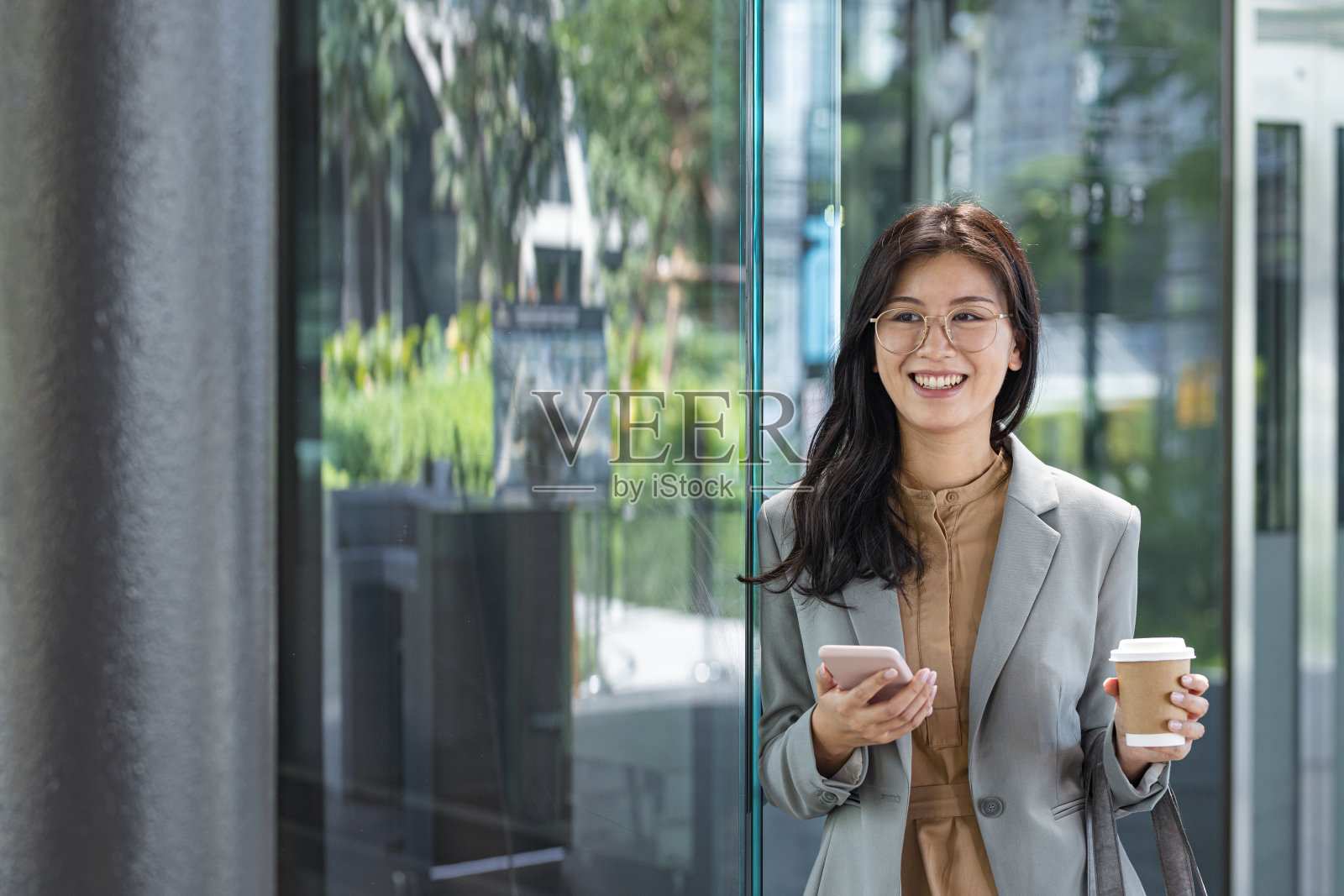 快乐年轻优雅的亚洲女商人在她的智能手机上发短信照片摄影图片