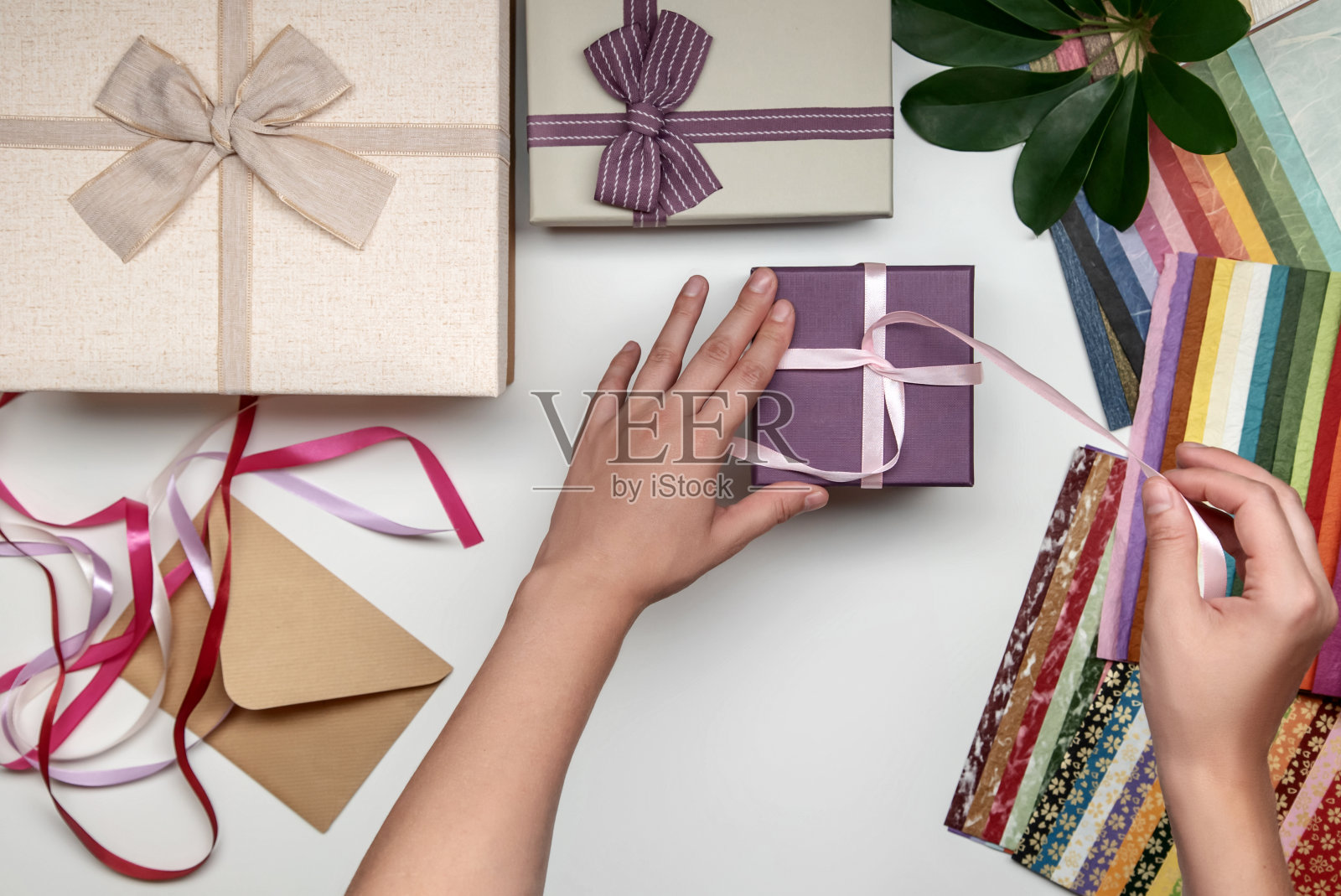 所有的礼物包装由女性的手在白色的背景。带蝴蝶结的礼物盒。彩带和彩色纸。照片摄影图片