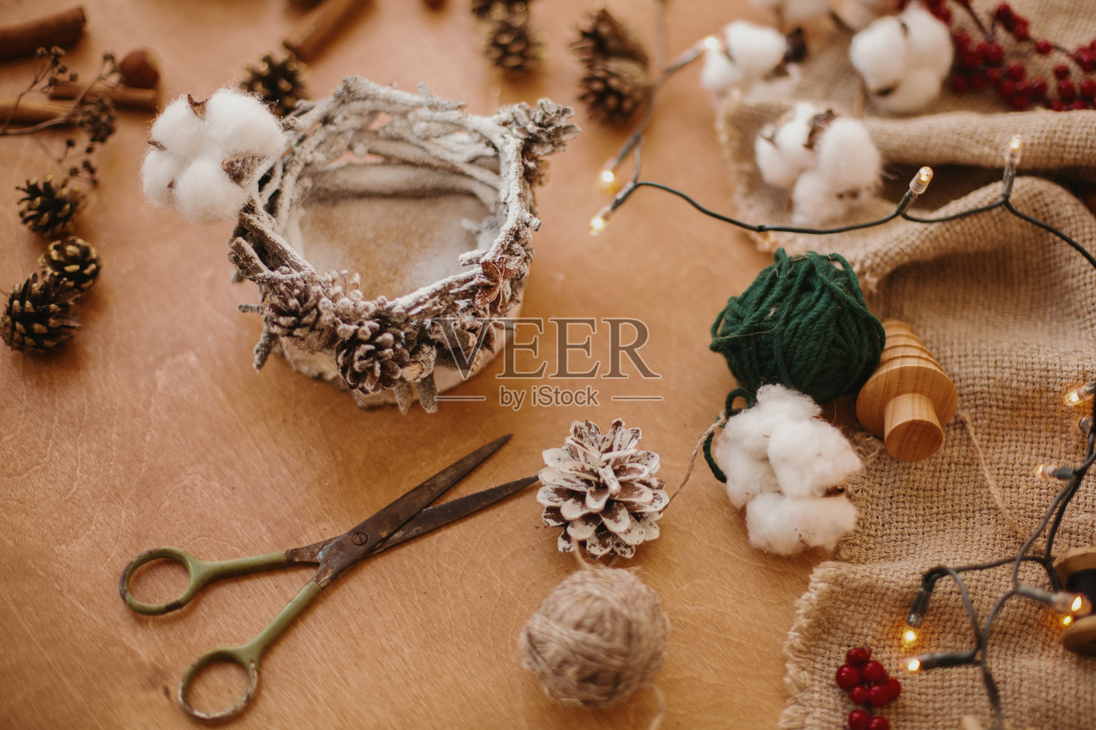 制作质朴的圣诞蜡烛装饰。由树枝，棉花，茴角和松果制成的圣诞烛台上的节日灯。假日车间。照片摄影图片