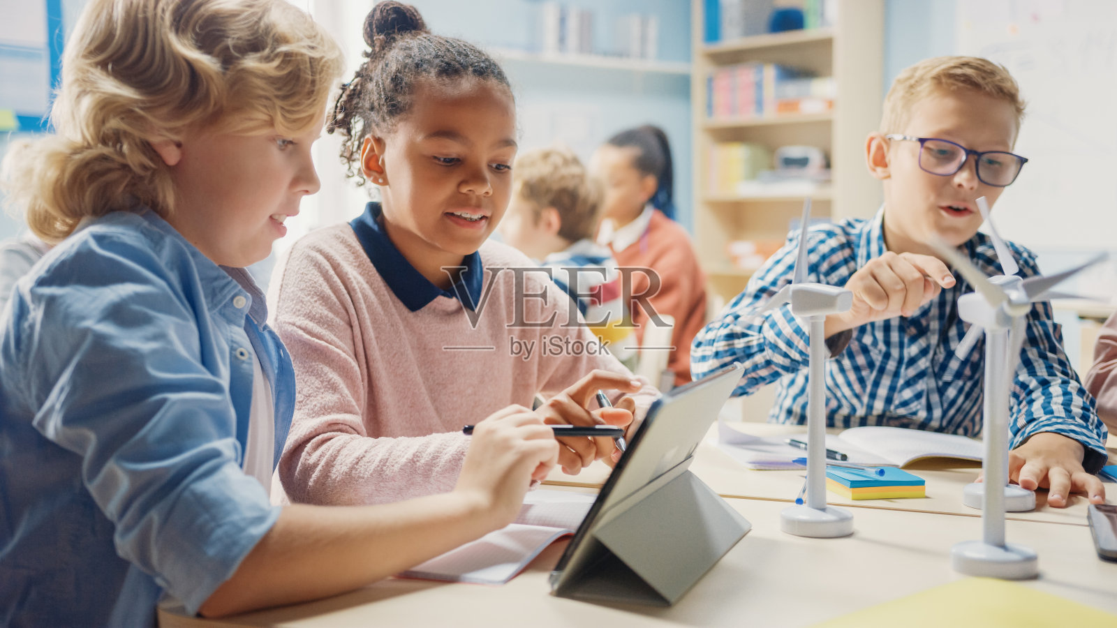 在小学:聪明的孩子们作为一个团队使用平板电脑编程风力涡轮机。与孩子们一起学习环保形式的可再生能源照片摄影图片