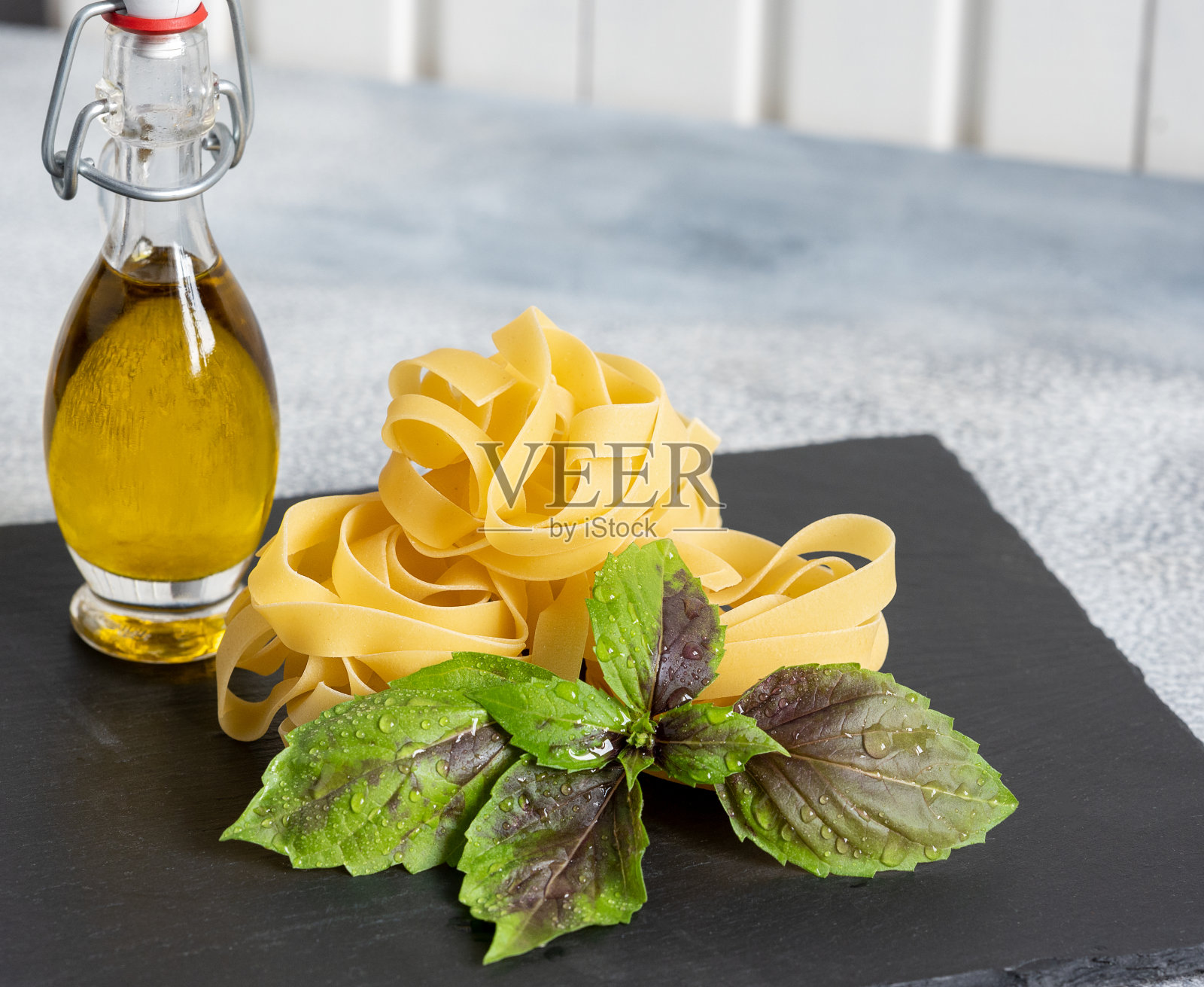 用罗勒和橄榄油在黑色石头背景上擀成的意大利面食照片摄影图片