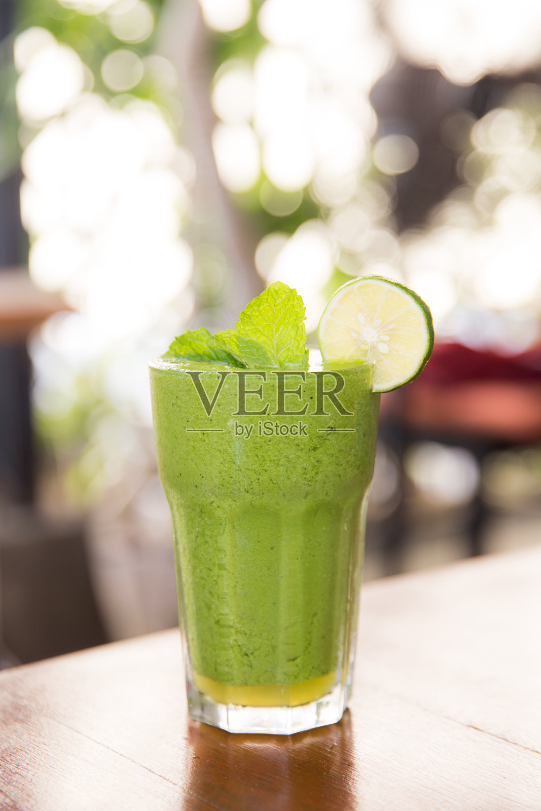 绿色素食健康冰沙与薄荷玻璃在女性手中。照片摄影图片