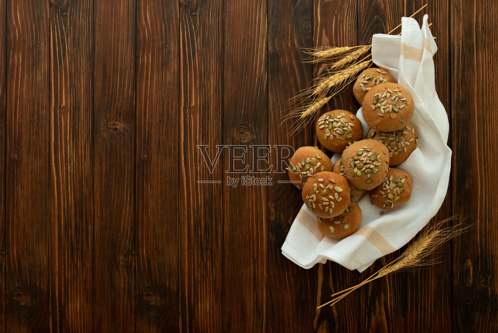 新鲜的自制脆皮面包面包糠，葵花籽和南瓜子在棕色的木头背景。前视图。照片摄影图片