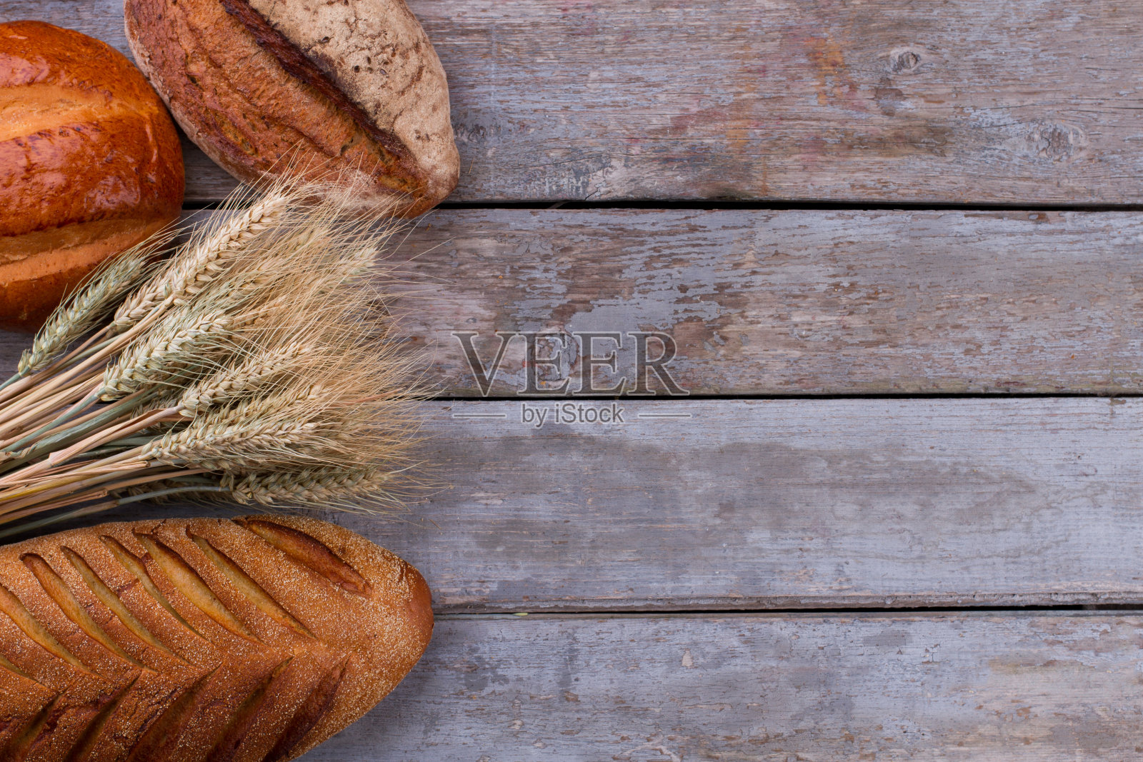 手工面包与小麦穗在木制背景。照片摄影图片