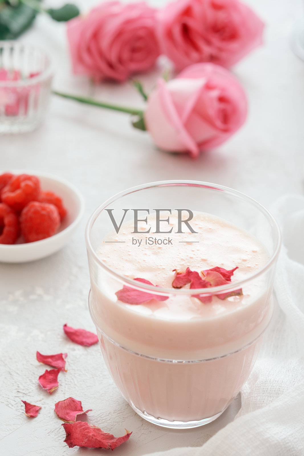 一杯月色牛奶，浅混凝土上点缀着玫瑰。阿育吠陀放松的夜晚饮料。照片摄影图片