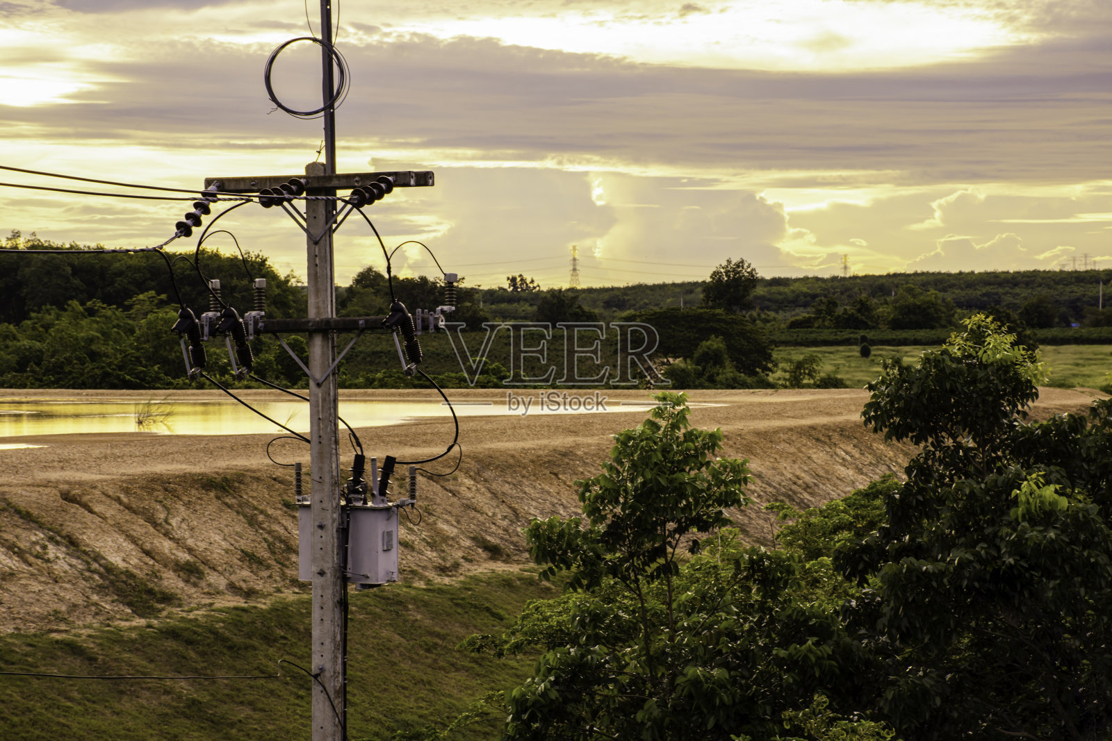 顶视图的电塔与绿色的树在日落的天空照片摄影图片