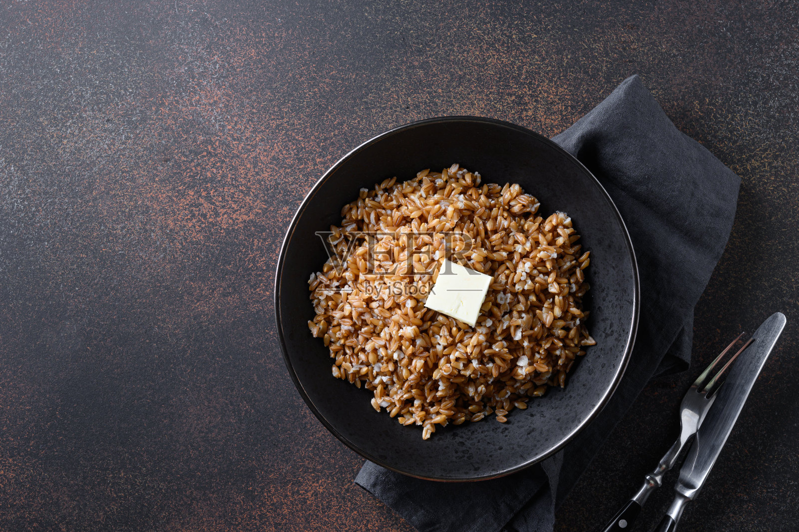 黑色的碗里放着黄油，背景是深棕色。前视图。空间的文本。照片摄影图片