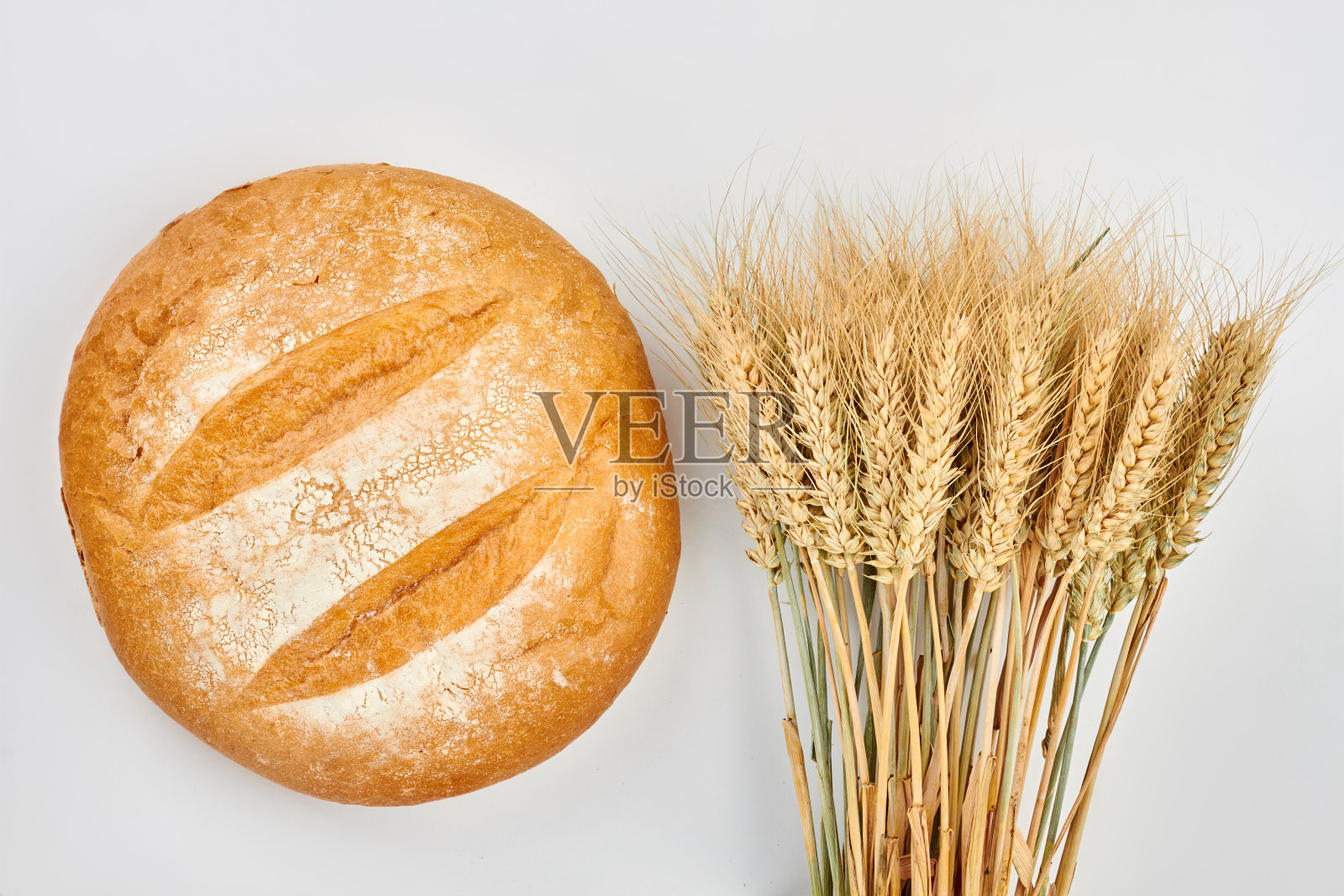 圆圆的面包和一串麦穗。照片摄影图片