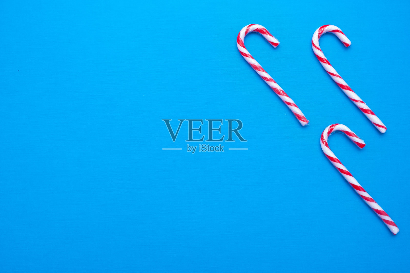 白色和红色的糖果拐杖在蓝色的背景，复制空间照片摄影图片